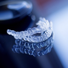 Clear aligner trays sitting on a reflective surface