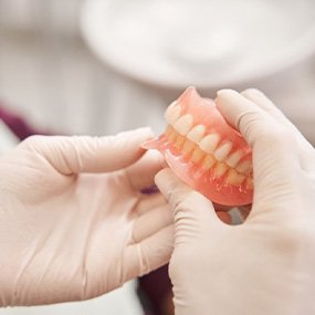 a person holding a pair of full dentures