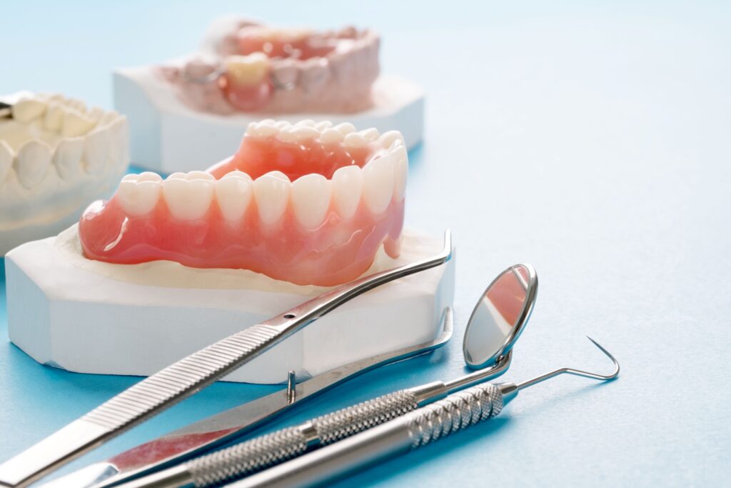 Lower dentures on a cast next to dental instruments